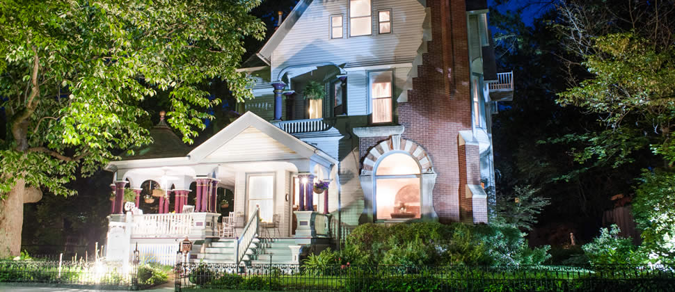 Historic 1892 Queen Anne Victorian inn with up lighting at night gorgeous front porch