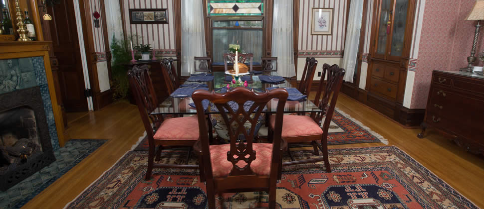 dining room with glass table and 6 victorian chairs, striped wall paper with gas fireplace