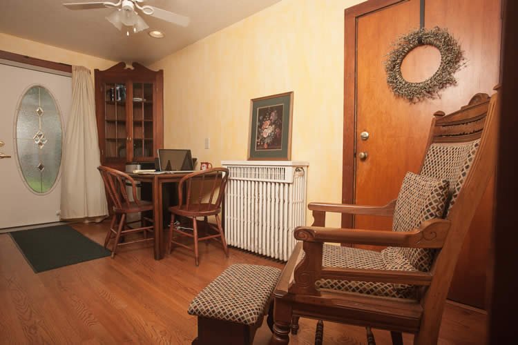 Sitting area, hardwood floors table and chairs with laptop, and old fashion wood chair with ottoman