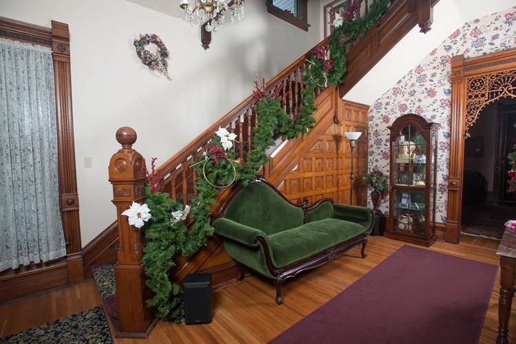 Foyer with Green love seat  grand staircase with carved wood and hardwood floors
