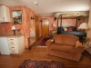 Room with canopy bed, dark bedspread, Kitchenette area with refrig and sink, room done in peach color and hardwood floor