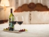 Wine bottle with two wine glass with red wine on a tray on the bed