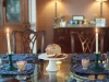 Dining table set up for Breakfast with blue paisley placemats, with white pedestal with banana nut bread